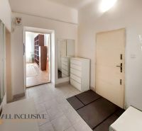 A hallway with white furniture, a mirror, and an entrance to a room in a 2-room apartment.