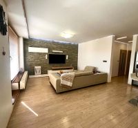 Living room in a 3-room apartment with a wooden decor floor, television, and sofa.