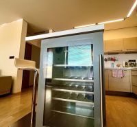 A kitchen in a 3-room apartment with a wine refrigerator and a floor with a wooden decor.