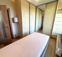 A bedroom in a 3-room apartment with a wood-patterned floor, a bed, and a built-in wardrobe.