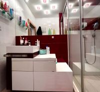 A bathroom with a shower, sink, and shelves in a 3-room apartment.