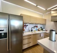 A kitchen in a 3-room apartment with a wood-patterned floor, white cabinetry, and stainless steel appliances.