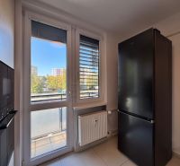 A kitchen with white walls, large windows, and a black refrigerator in a 3-room apartment.