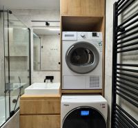A bathroom in a 3-room apartment with a washing machine and dryer, light tiles, wooden decor.