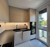 A kitchen in a 3-room apartment with a modern kitchen unit, built-in appliances, and a large window.