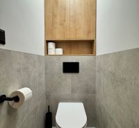 A toilet in a 3-room apartment with storage space and wood decor.