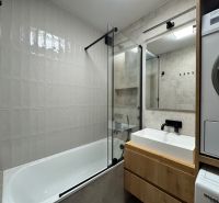 A modern bathroom in a 3-room apartment with a bathtub, sink, and washing machine.