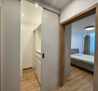 A hallway with sliding doors and a bed, a floor with a wooden decor in a 3-room apartment.