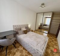 Bedroom in a 3-room apartment with a bed, wardrobe, and wooden decor flooring.