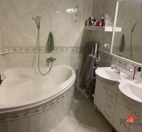 A bathroom with a corner bathtub, double sink, and ceramic tiles in a 3-room apartment.