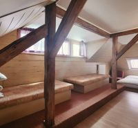 Attic room in a holiday apartment with a wooden decor floor and beds.