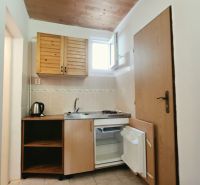 Kitchen corner in a holiday apartment with wooden cabinets, a sink, and a mini-fridge.