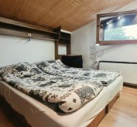 Attic bedroom with a double bed, shelf, and window, Holiday apartment.