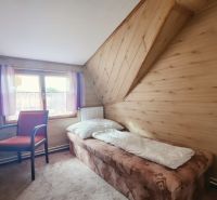 Single room in a holiday apartment with wood-patterned flooring and a window.