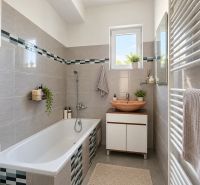 A bathroom in a family house with gray tiles, a bathtub, and a sink on a cabinet.