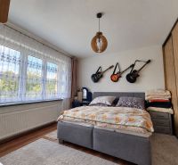 Bedroom in a family house with guitars on the wall, floor with wooden decor.