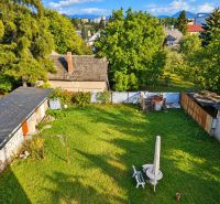A garden of a family house in Martin with a lawn and visible roofs of nearby buildings.