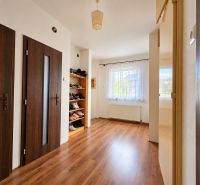 Interior of a family house with a wooden decor floor, doors, and a shoe rack.