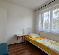 Single room with a bed and a desk, wooden decor flooring, white interior.