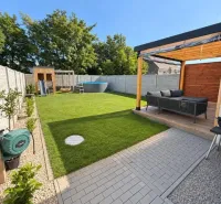A landscaped garden of a family house in Čierna Voda, Čierna Voda, with a terrace and lawn.