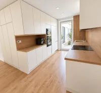 A family house kitchen with a wooden decor floor and white cabinets.