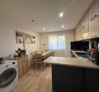A kitchen in a 2-room apartment with a wooden decor floor and modern equipment.
