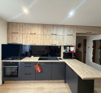 A kitchen in a 2-room apartment with black cabinets and a wooden decor floor.