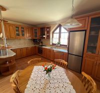 A family house kitchen with wooden furniture, a floor with a wooden design, and a dining table.