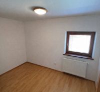 A room in a family house with a wooden decor floor and a window with a radiator.