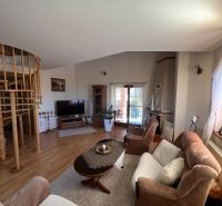 Living room in a family house with a comfortable couch, staircase, and wooden decor flooring.