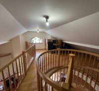A staircase in the attic of a family house with a wooden decor floor and a work corner.