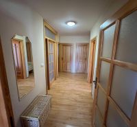 A hallway in a family house with a wooden decor floor and multiple doors.