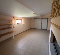 Interior of a family house with tiles, storage shelves, and a window with sheer curtains.