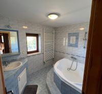 A bathroom with a bathtub and a sink in a family house, tiled walls.