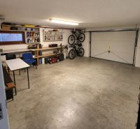 A garage in a family house with folding bicycles, a lawnmower, and shelves for tools.