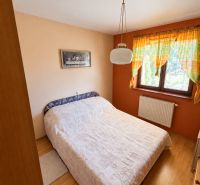 Bedroom in a family house with a bed, curtains, and a wooden decor floor.