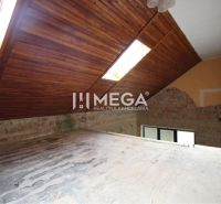 The attic of a family house with wooden roof windows, a brick wall, and light tubes in the roof.