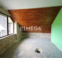 A room in a family house with a wooden ceiling and exposed bricks.