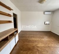 A room in a 3-room apartment with a wooden decor floor and wall shelves.