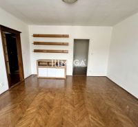 A room in a 3-room apartment with a wooden decor floor and shelves on the wall.