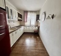 A kitchen in a 3-room apartment with a wooden decor floor, white furniture, red refrigerator.