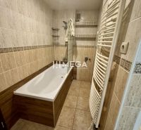 Bathroom with tiles, a bathtub, and a ladder radiator in a 3-room apartment.