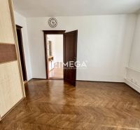 A room in a 3-bedroom apartment with a wood-patterned floor and open doors.