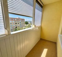 A glazed balcony with a view of apartment buildings, part of a studio apartment.