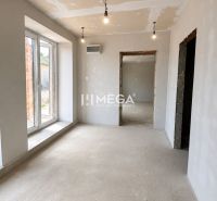 Interior of a family house with a concrete floor, plastered walls, and large windows.