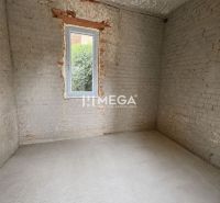 A raw room in a family house with a gray floor and exposed bricks.