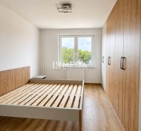 A bedroom in a three-room apartment with a wooden decor floor and a built-in wardrobe.