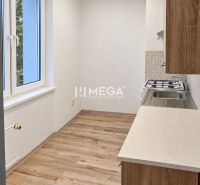 A kitchen in a 2-room apartment with a wooden decor floor and a window.