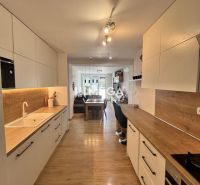 A kitchen in a 3-room apartment with a wood-decor floor and white cabinets.