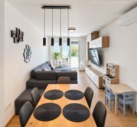 A spacious living room in a 3-room apartment with a wooden decor floor and a comfortable sofa.